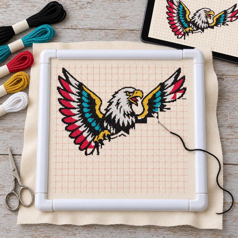 Eagle cross stitch in progress on a scroll frame with floss and scissors