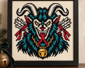 May include: A framed cross-stitch embroidery featuring a stylized horned creature with blue, black, and white fur, yellow eyes, and a red tongue. The figure wears a gold bell around its neck and holds bundles of white sticks tied with red ribbons.