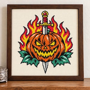 May include: A cross-stitch embroidery in a dark wood frame featuring a jack-o'-lantern with a jagged grin, pierced by a silver sword with a red and gold hilt. The pumpkin is surrounded by bright yellow and red flames and green leaves.