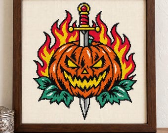 Puede incluir: Un bordado de punto de cruz en un marco de madera oscura que muestra una calabaza de Halloween con una sonrisa dentada, atravesada por una espada plateada con empuñadura roja y dorada, rodeada de llamas amarillas y rojas y hojas verdes.