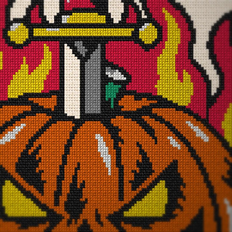 May include: A cross-stitch embroidery featuring an orange jack-o'-lantern with yellow eyes and a mouth. A gray sword with a yellow hilt is embedded in the top of the pumpkin. The background consists of bright yellow flames against a red field.