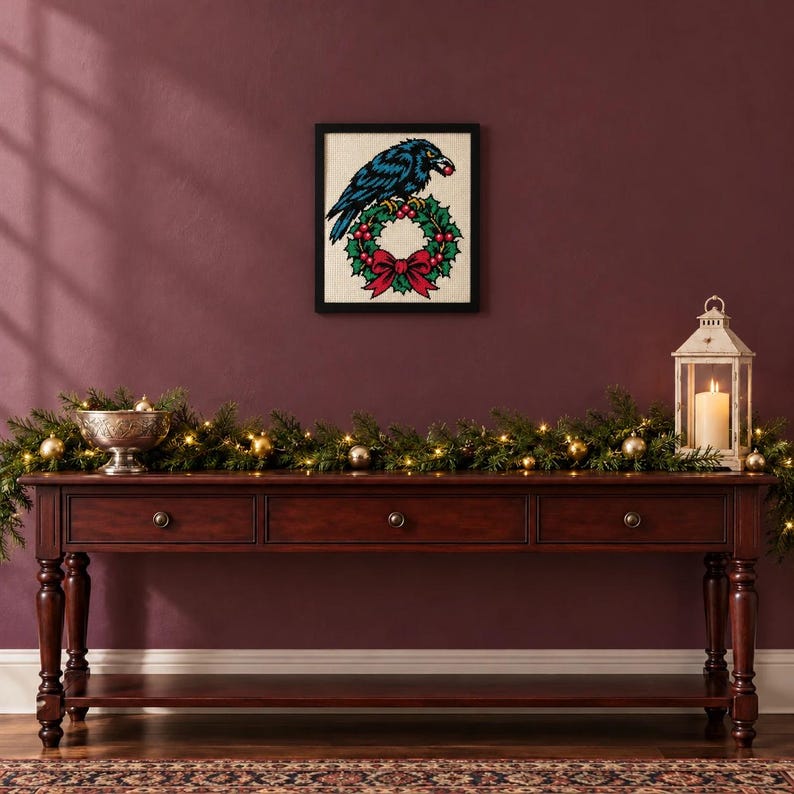 Framed raven on a holly wreath cross stitch on a wall