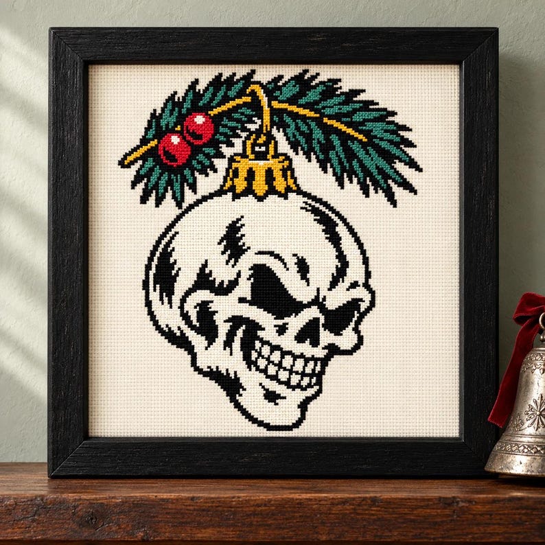 Straight-on view of the finished Skull Ornament Cross Stitch in a black frame on a wooden shelf