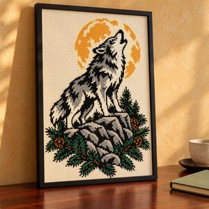Howling wolf cross stitch in a tall black frame on a shelf