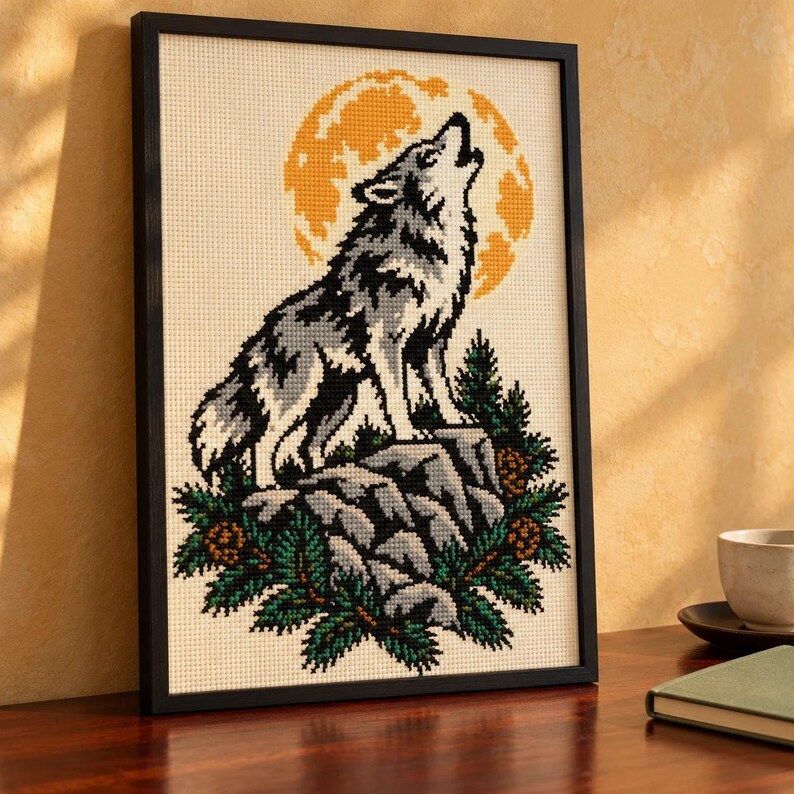 Howling wolf cross stitch in a tall black frame on a shelf