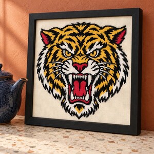 Tiger cross stitch in a black frame on a shelf