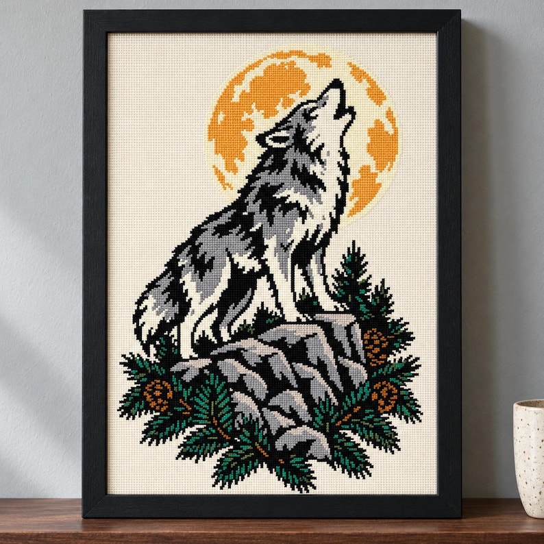 Straight-on view of the finished Howling Wolf Cross Stitch in a black frame on a wooden shelf