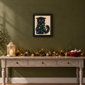 Framed grumpy black cat in Christmas lights cross stitch on a wall