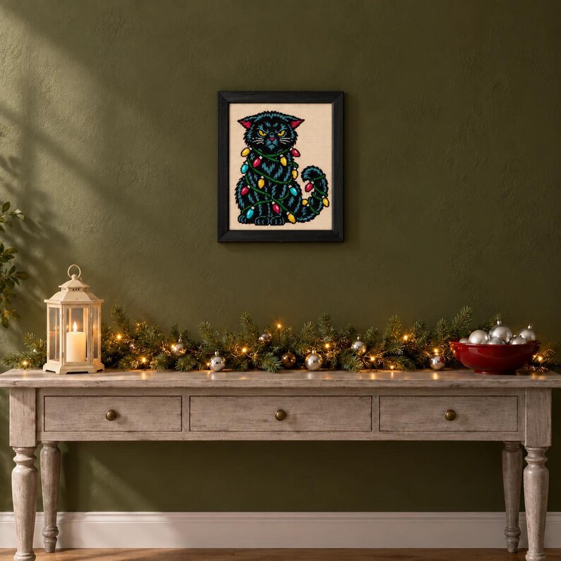 Framed grumpy black cat in Christmas lights cross stitch on a wall