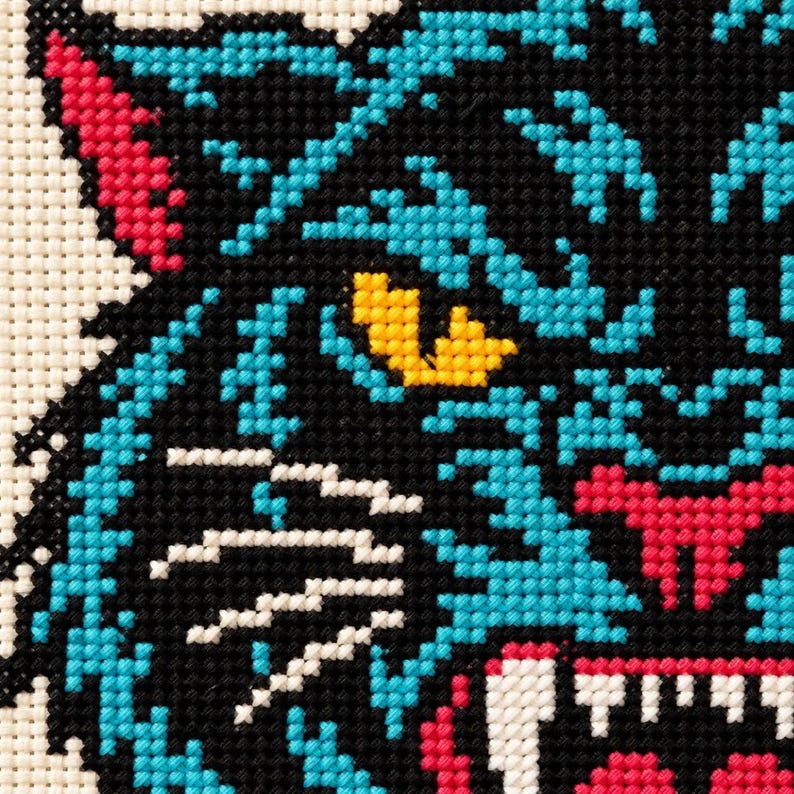 Macro of stitched panther face showing teal fur, yellow eye and fangs