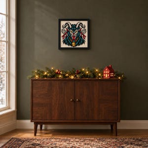 Framed Krampus tattoo flash cross stitch on a wall