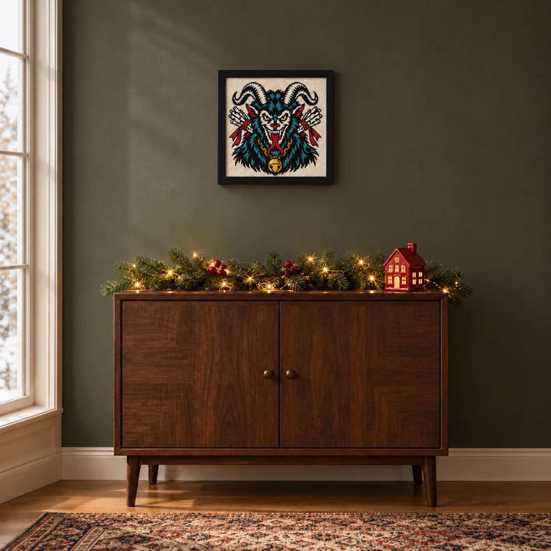 Framed Krampus tattoo flash cross stitch on a wall