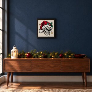 Framed skull in a Santa hat cross stitch on a wall