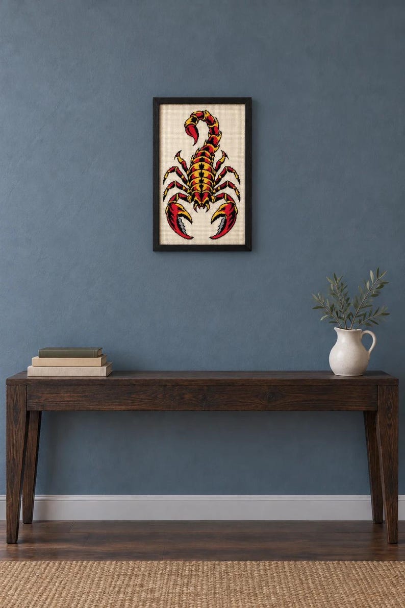 Framed scorpion tattoo flash cross stitch on a wall