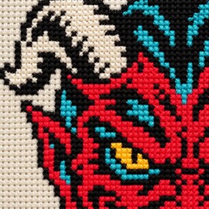Macro of the stitched devil face showing yellow eyes and sharp teeth
