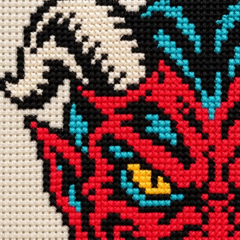 Macro of the stitched devil face showing yellow eyes and sharp teeth