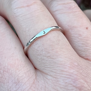 May include: A silver ring with a hammered texture and the letter "J" engraved on the band.