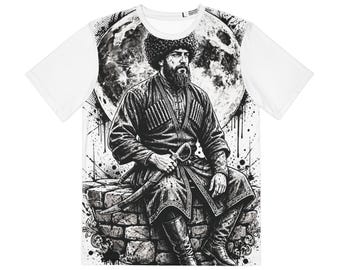 May include: A white short-sleeve t-shirt featuring a black and white graphic print of a bearded man in a traditional fur hat and coat, sitting on a stone wall with a sword at his side, set against a large moon and ink splatter background.