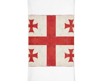 May include: A rectangular neck gaiter featuring the flag of Georgia, which consists of a large red cross on a white background with four smaller red crosses in each quadrant. The fabric has a slightly weathered, textured appearance.