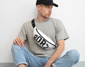May include: A white fanny pack with a black zipper and the black distressed text "BORZ" printed on the front. The bag features an adjustable black strap with a plastic buckle, worn across the chest over a grey t-shirt and blue jeans.