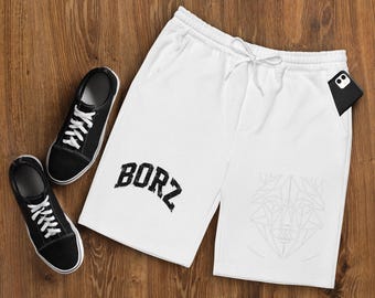 May include: White shorts with an elastic drawstring waistband, featuring the black text BORZ in an arched font on the left leg and a faint, geometric line-art wolf head design on the right leg, accompanied by two black sneakers.