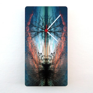 May include: A clock with a red second hand and white hour and minute hands. The clock face is a photograph of a tree reflected in a body of water with a colorful sunset sky in the background.