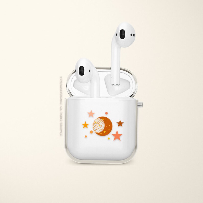 May include: White wireless earbuds case with a moon and stars design. The case is open and the earbuds are inside.