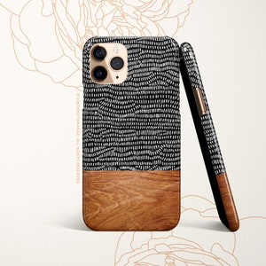 May include: A black and white patterned phone case with a wood grain accent. The case has a geometric pattern of small white lines on a black background. The bottom half of the case is a light brown wood grain.