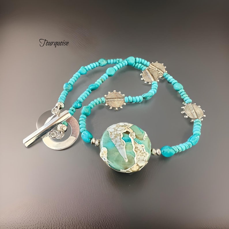 May include: A turquoise and silver necklace featuring a large turquoise pendant and silver accents. The necklace is made of small turquoise beads and silver spacers. The pendant is a large, round turquoise stone with a silver swirl design.
