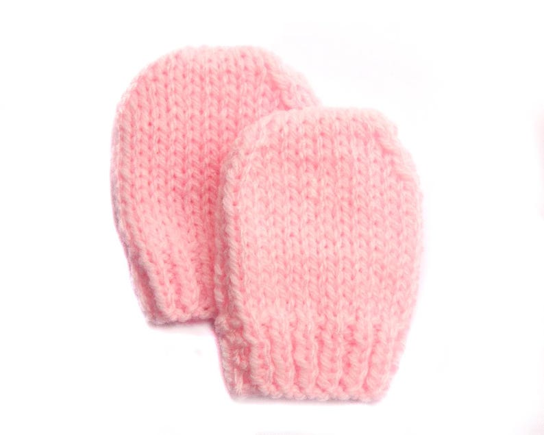 May include: A pair of pink knitted baby mittens. The mittens are soft and warm, perfect for keeping little hands cozy.