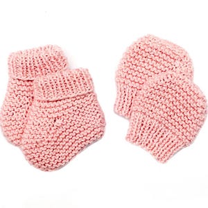 May include: A pair of pink knitted baby booties. The booties are made of a soft, chunky yarn and have a simple, classic design.