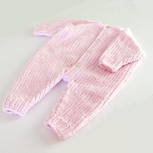 Puede incluir: Mono de beb&eacute; de punto rosa claro, con mangas y perneras largas. El mono tiene una botonadura frontal y pu&ntilde;os y tobillos acanalados. La tela suave y texturizada es de color pastel liso.