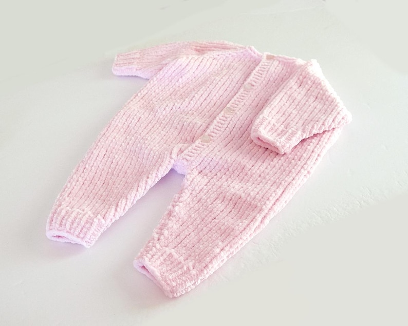Puede incluir: Mono de beb&eacute; de punto rosa claro, con mangas y perneras largas. El mono tiene una botonadura frontal y pu&ntilde;os y tobillos acanalados. La tela suave y texturizada es de color pastel liso.