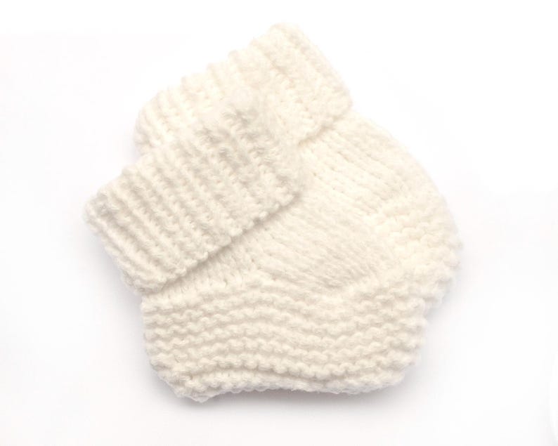 May include: A pair of white knitted baby booties with a folded cuff.