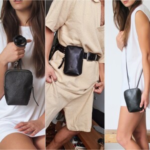 Könnte beinhalten: Drei verschiedene Möglichkeiten, eine kleine schwarze Leder-Umhängetasche zu tragen. Die Tasche hat einen Reißverschluss und einen verstellbaren Riemen, der über den Körper, um die Taille oder als Schultertasche getragen werden kann.
