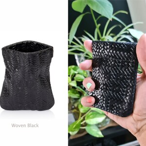 May include: A black woven pouch with a textured design. The pouch is empty and sitting on a white surface. Woven Black.