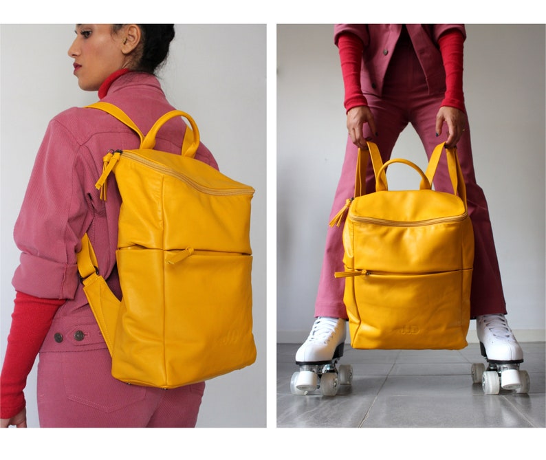 May include: A bright yellow leather backpack with two zippered compartments and a top zipper closure. The backpack is being worn by a person and also held in front of a person on roller skates.