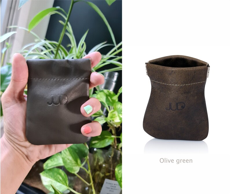 May include: A small, olive green leather pouch with a drawstring closure and a stitched design. The pouch has the initials "JD" embossed on the front.