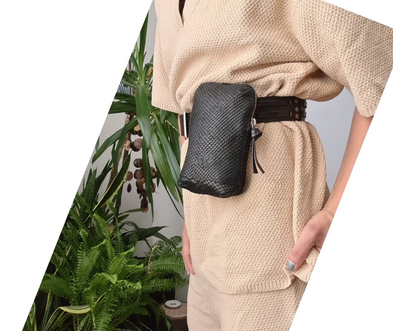 May include: A black woven leather fanny pack with a brown leather belt. The fanny pack is worn over a beige knitted top.