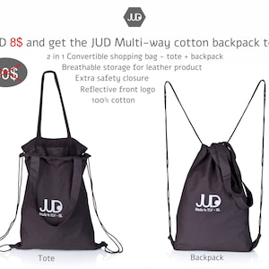 May include: A black cotton tote bag with a drawstring closure and adjustable straps. The bag can be used as a tote or a backpack. The bag has a reflective logo that says "JUD Made in TLV - ISL".