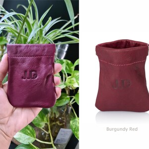 May include: Burgundy red leather pouch with the initials "J.D." embossed on the front.