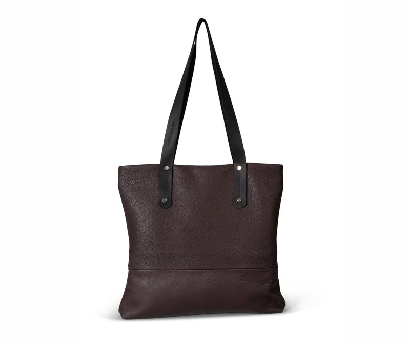 May include: A brown leather tote bag with black leather handles and silver hardware.