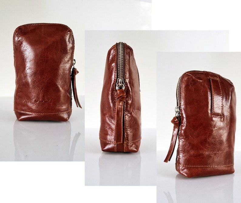 May include: A brown leather zippered pouch with a silver zipper pull. The pouch is shown from three different angles.