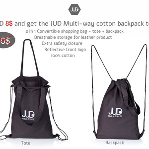 May include: A black cotton tote bag with drawstring closure and adjustable straps. The bag can be worn as a backpack or carried as a tote. The bag has a white logo that says "JUD Made in TLV - ISL".