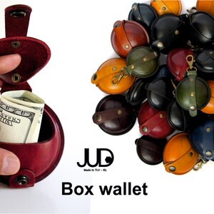 May include: A red leather box wallet with a flap that opens to reveal a compartment for cash. The wallet is made by JUD, a brand that is "Made in TLV - IL". The image also shows a variety of other box wallets in different colors and designs.