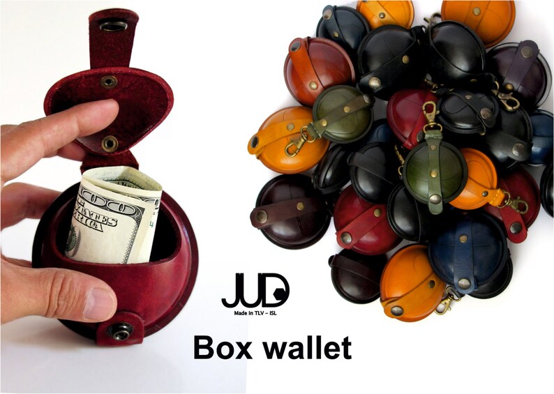 May include: A red leather box wallet with a flap that opens to reveal a compartment for cash. The wallet is made by JUD, a brand that is "Made in TLV - IL". The image also shows a variety of other box wallets in different colors and designs.
