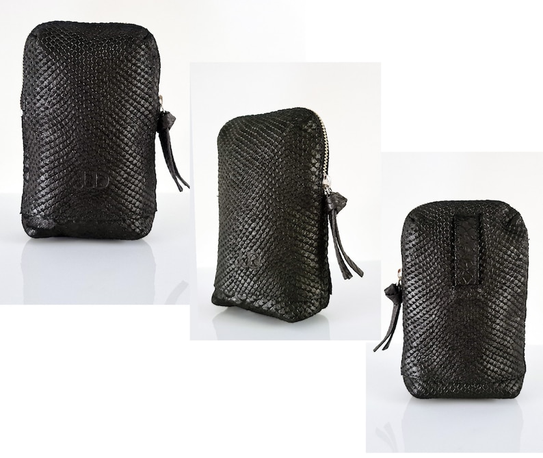 K&ouml;nnte beinhalten: Schwarze Leder-Zipper-Tasche mit einem strukturierten Schlangenhautmuster. Die Tasche hat einen kleinen Rei&szlig;verschluss mit einem Quasten.