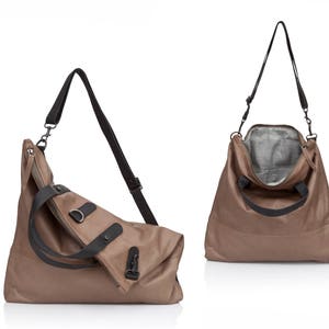 May include: A brown leather tote bag with black straps and a zipper closure. The bag has a flap that folds over the top and is secured with a buckle.