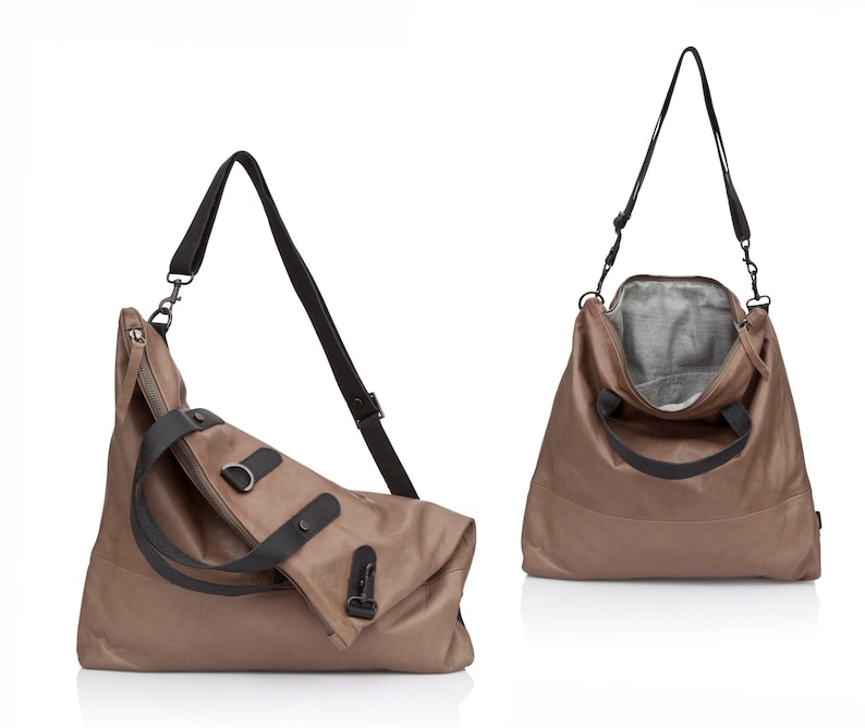 May include: A brown leather tote bag with black straps and a zipper closure. The bag has a flap that folds over the top and is secured with a buckle.