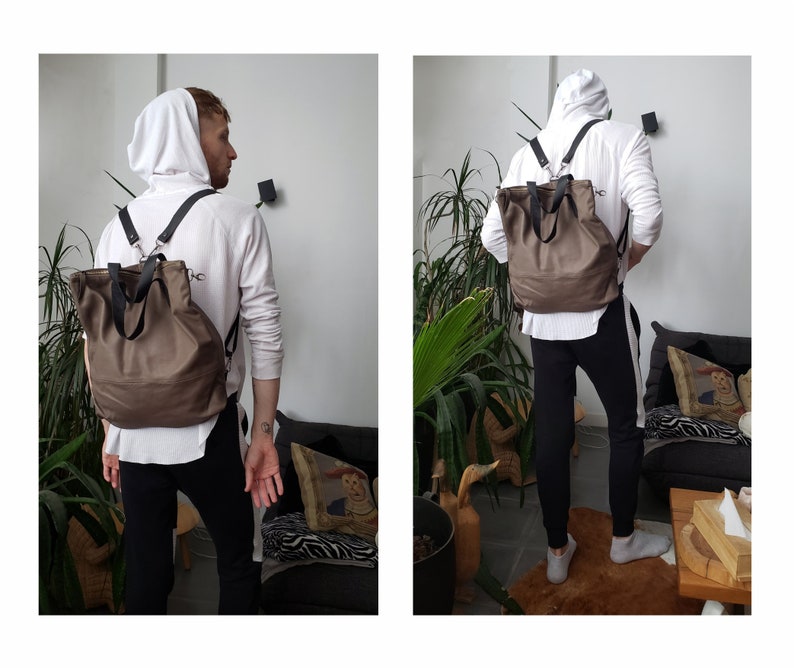 May include: A brown leather backpack with adjustable straps. The backpack has a large main compartment and a smaller front pocket. The backpack is being worn by a person.